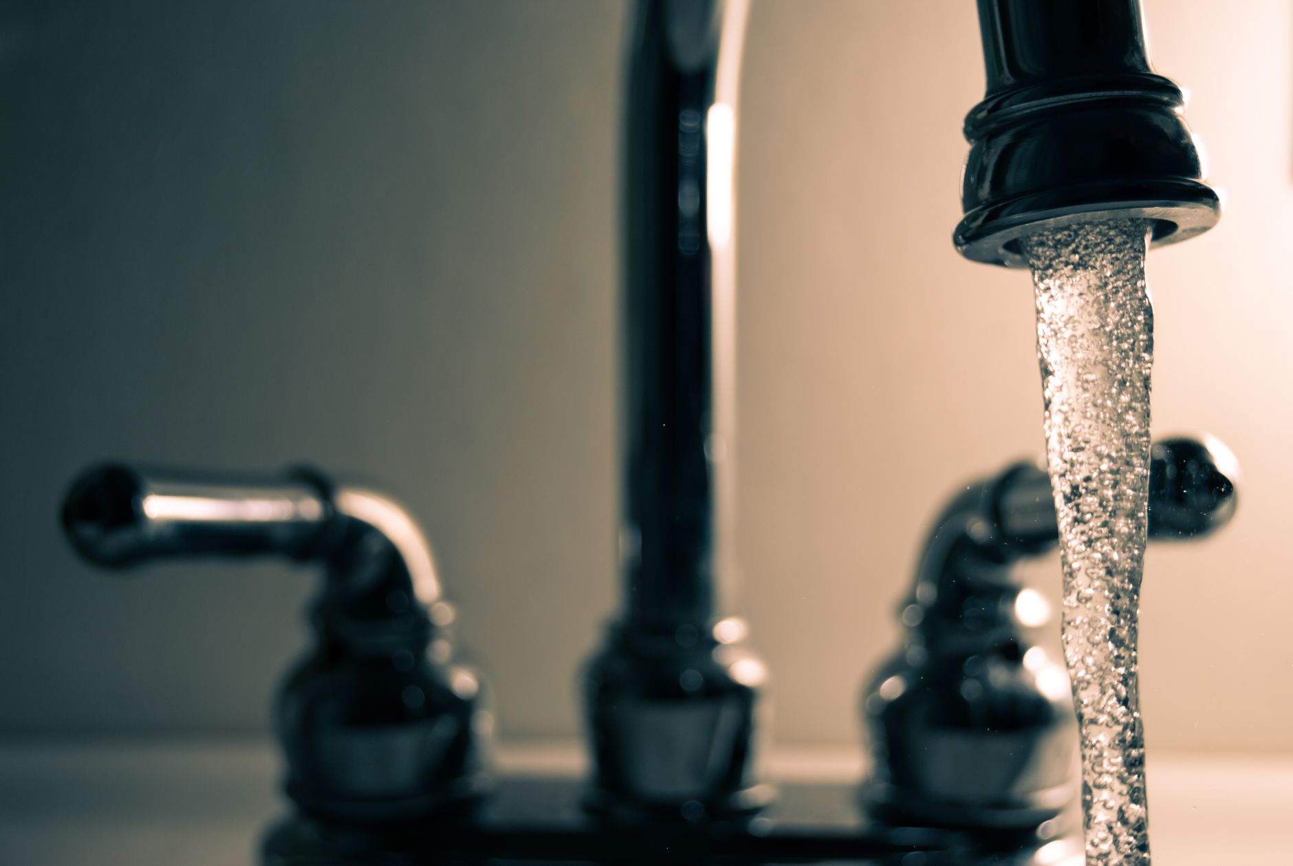 Clear water flowing from a steel faucet — recommended for Lansing hard water treatment