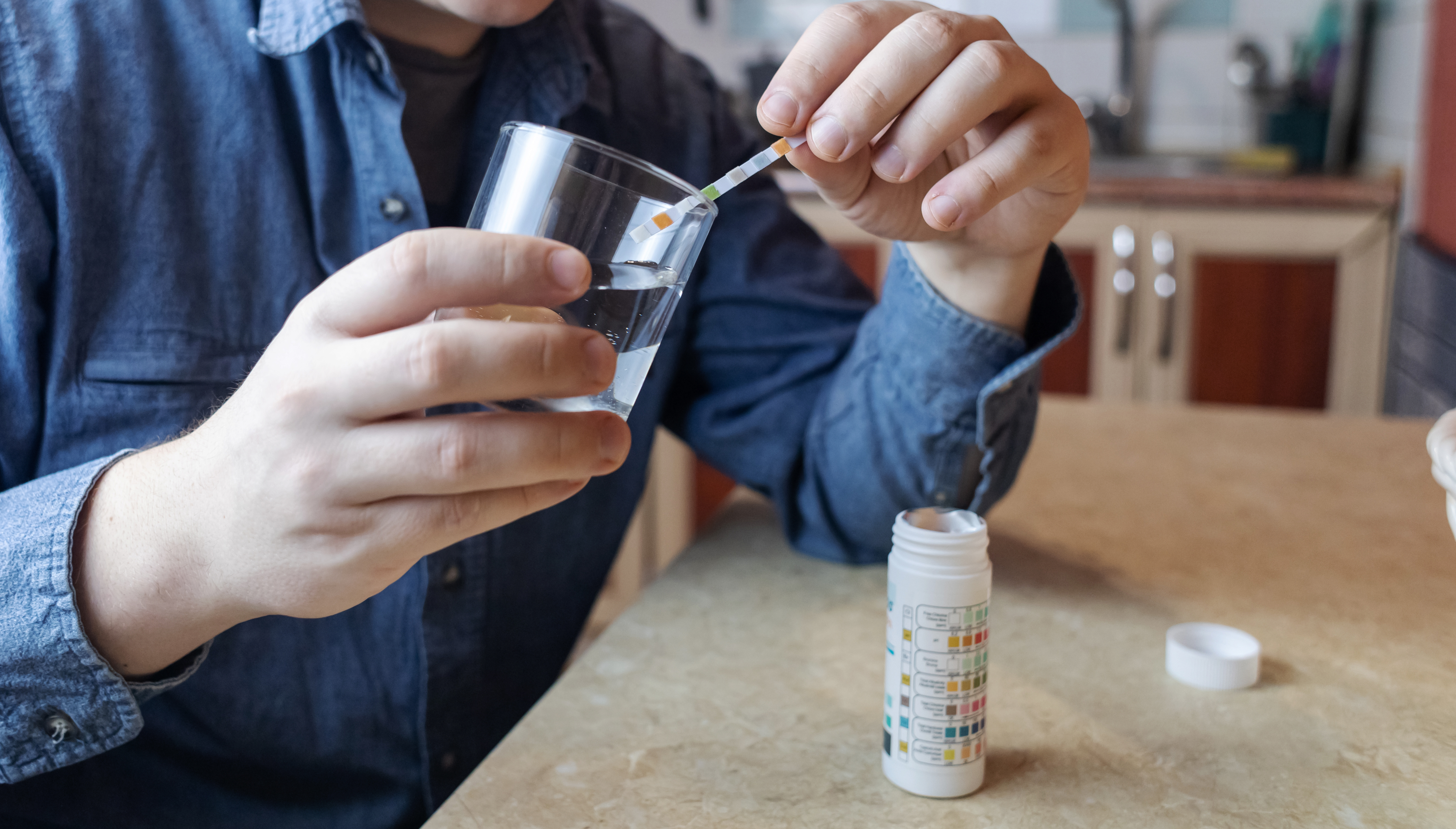 Water hardness test strip showing very hard reading in a glass of tap water — recommended for Madison, WI hard water at 21.3 GPG